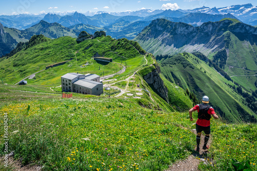 Man starting a trail run descent in Swiss Alps and panorama of mountains during summer time in Switzerland Europe photo