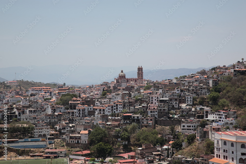 View of Santa Prisca Church and  dense white houses with tile roofs on the hill  in Taxco, Mexico 
