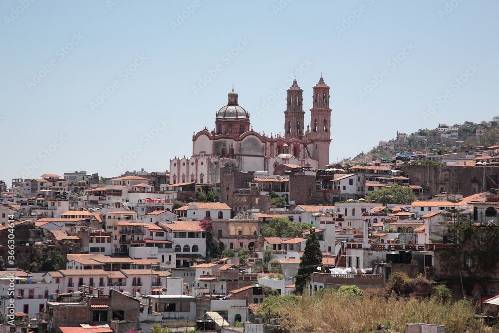 Naklejka premium View of Santa Prisca Church and dense white houses with tile roofs on the hill in Taxco, Mexico 