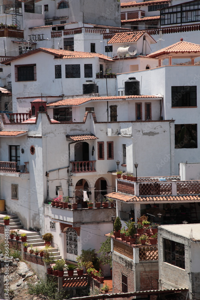 View of white and red houses with tile roofs on hill in Taxco, Mexico 