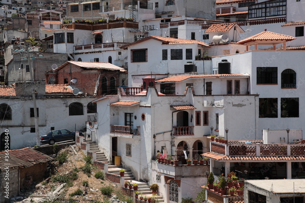 View of white and red houses with tile roofs on hill in Taxco, Mexico 