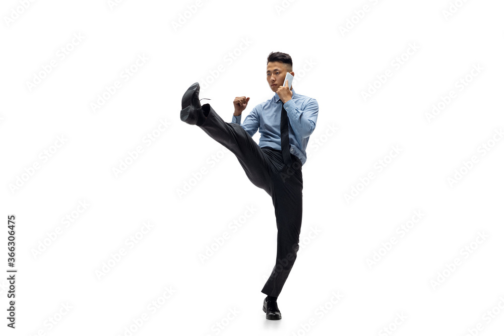 Obraz premium Target. Man in office clothes practicing taekwondo on white background like professional player, sportsman. Unusual look for businessman in motion, action with ball. Sport, healthy lifestyle