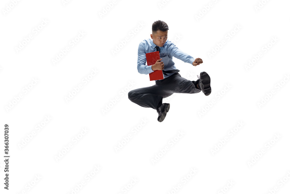 In jump. Man in office clothes practicing taekwondo on white background like professional player, sportsman. Unusual look for businessman in motion, action with ball. Sport, healthy lifestyle In jump. Man in office clothes practicing taekwondo on white background like professional player, sportsman. Unusual look for businessman in motion, action with ball. Sport, healthy lifestyle