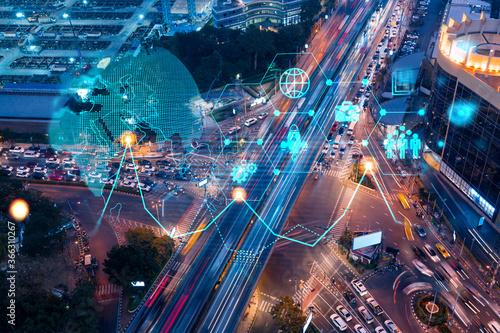Research and development hologram on aerial view of road, busy urban traffic highway at night. Junction network of transportation infrastructure. Concept of innovative logistics. Double exposure.