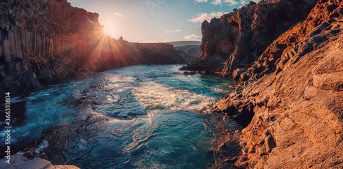 Tipical Icelandic scenery under sunlit, during sunset in Iceland. Powerful river in canyon with black basalt columns under sunlight. Amazing nature scene. Wonderful nature of Iceland.