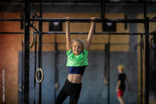 Young girl in green shirt and leggings training at the gym. Copy space.