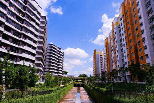 Singapore. Typical colourful public housing in heartland canberra estate on bright sunny day, cloudy blue sky. Lush green surrounding. Vanishing perspective architecture shot; panoramic wide angle.