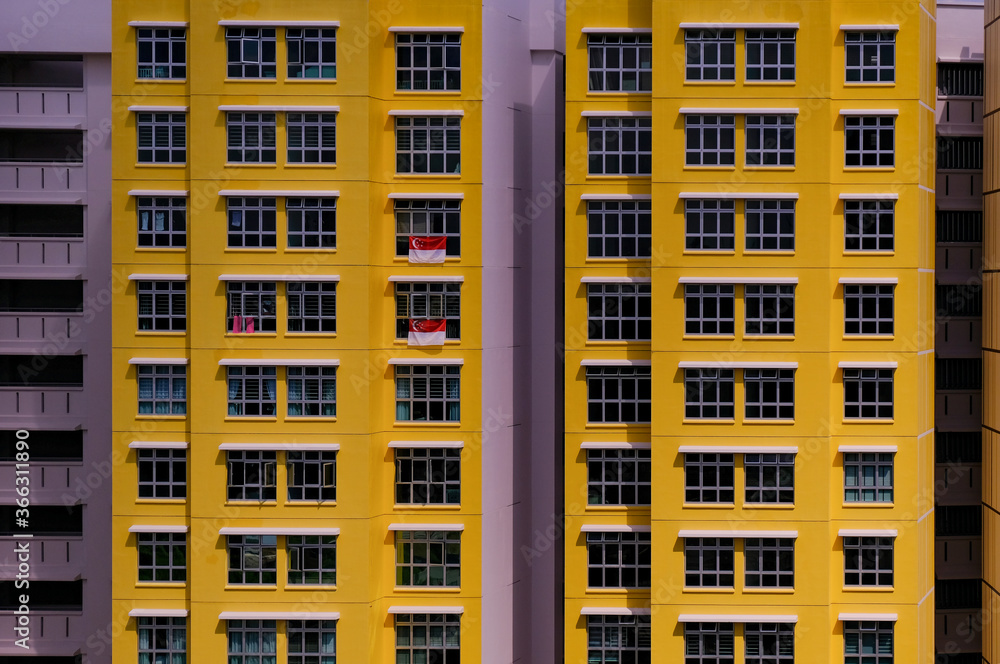 Close up of exterior of typical public housing (HDB flats) in bright, bold yellow, in Singapore on sunny day. Modern urban architecture concept. Abstract graphic; background.