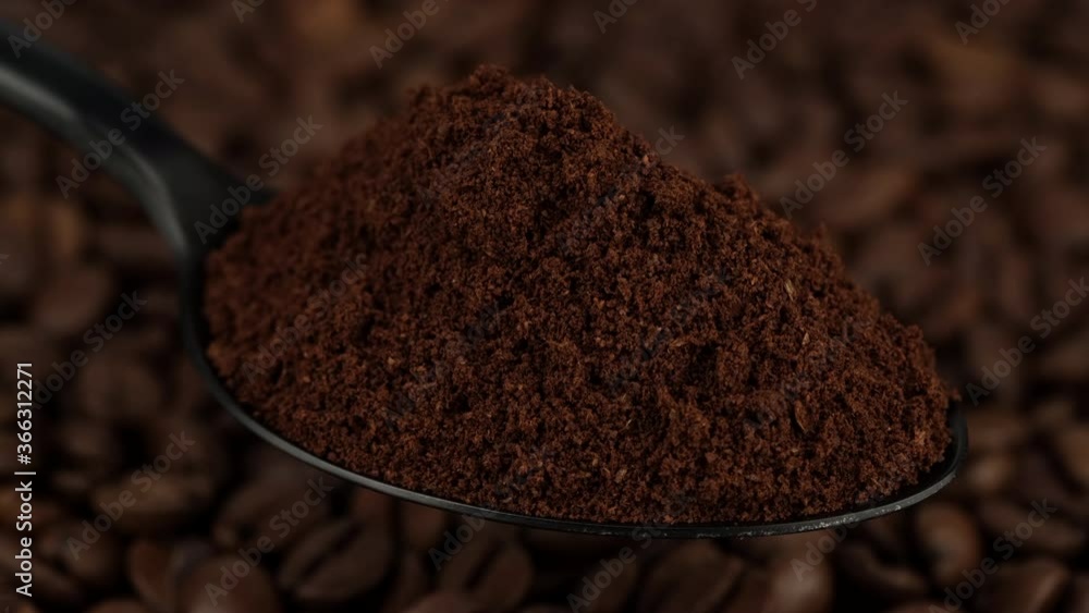 ground coffee in black spoon and coffee beans on background rotating ground coffee in black spoon and coffee beans on background rotating