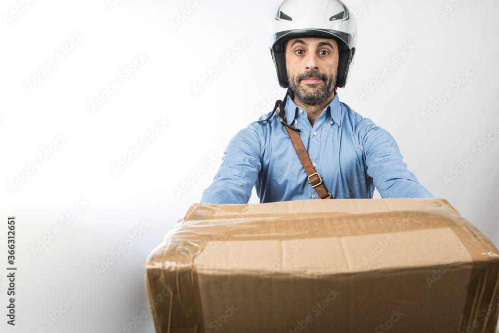 Corriere express con camicia blu, borsa a tracolla e casco da moto si appresta a consegnare un pacco , isolato su sfondo bianco Corriere express con camicia blu, borsa a tracolla e casco da moto si appresta a consegnare un pacco , isolato su sfondo bianco