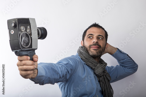 uomo in camicia blu e sciarpa utilizza una vecchia cinepresa da super 8, isolato su sfondo bianco