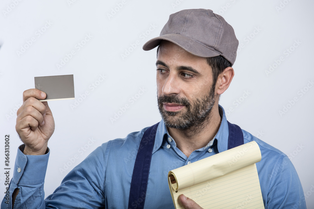 fattorino con cappellino camicia e blocco notes giallo in mano , mostra una tessera con l'altra mano, isolato su sfondo bianco fattorino con cappellino camicia e blocco notes giallo in mano , mostra una tessera con l'altra mano, isolato su sfondo bianco