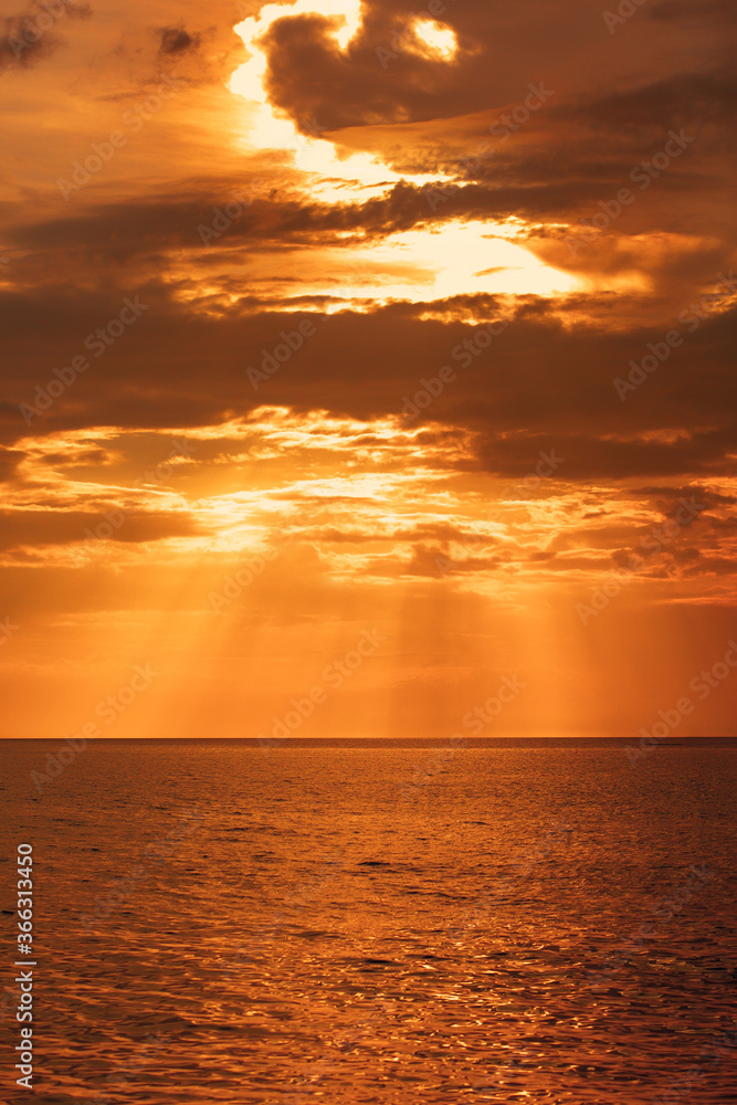 Stunning sunset at sea. A tourist flies by parachute and a boat in the distance into the sea. Sun rays