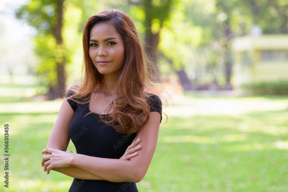 Young beautiful Asian woman with arms crossed at the park outdoors Young beautiful Asian woman with arms crossed at the park outdoors