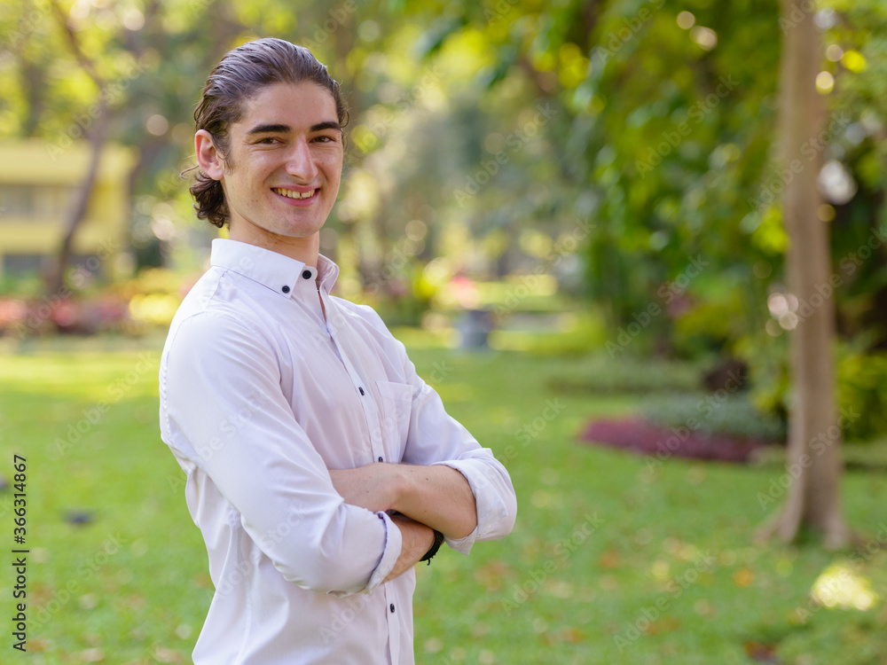 Happy young handsome businessman smiling with arms crossed at the park outdoors Happy young handsome businessman smiling with arms crossed at the park outdoors