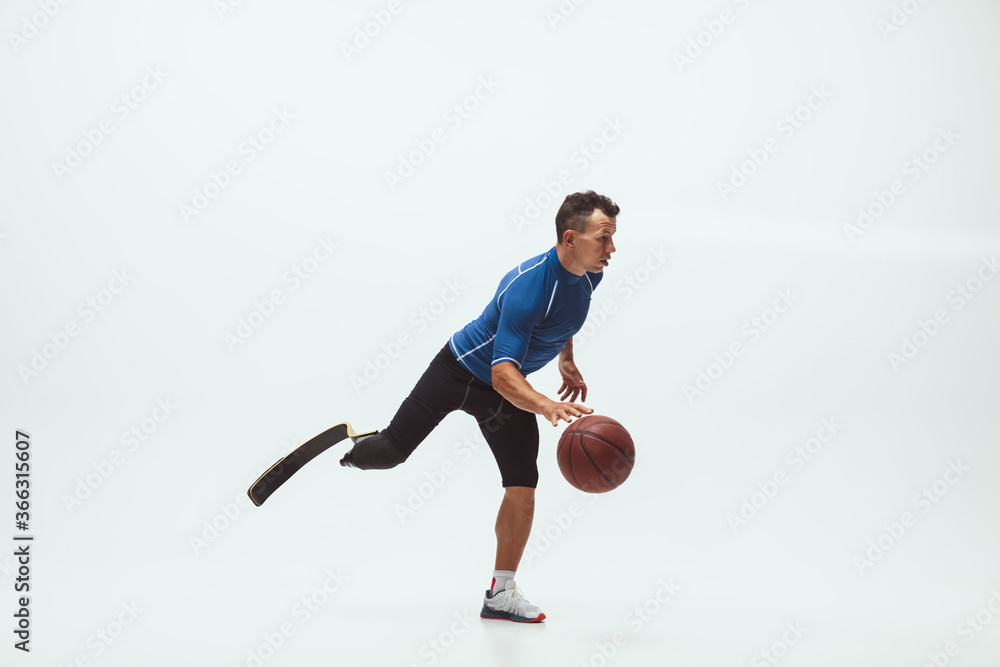 Athlete with disabilities or amputee on white studio background. Professional male basketball player with leg prosthesis training in studio. Disabled sport and healthy lifestyle concept. Achievements. Athlete with disabilities or amputee on white studio background. Professional male basketball player with leg prosthesis training in studio. Disabled sport and healthy lifestyle concept. Achievements.
