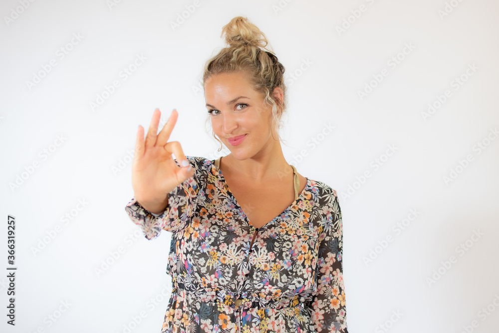 Pretty blonde woman in a flowery dress gesturing on white background Pretty blonde woman in a flowery dress gesturing on white background