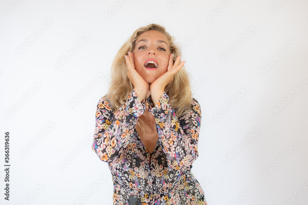 Pretty blonde woman in a flowery dress gesturing on white background