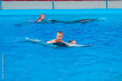 Happy little kids swimming with dolphins in Dolphinarium