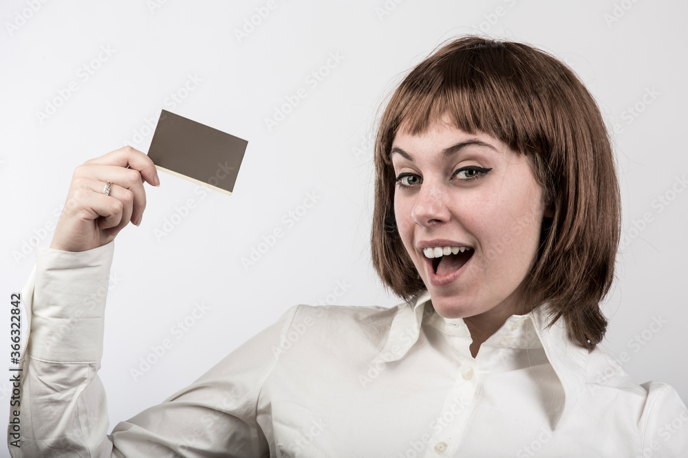 ragazza con capelli a caschetto castani , e camicia bianca mostra una carta tenuta in sospeso sulla mano destra, isolata su sfondo bianco