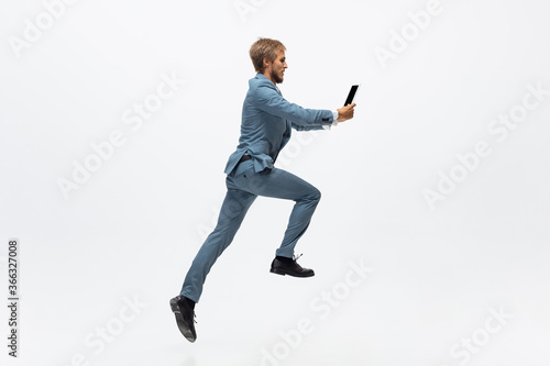 Winner, jump. Man in office clothes running, jogging on white background like professional athlete, sportsman. Unusual look for businessman in motion, action with ball. Sport, healthy lifestyle