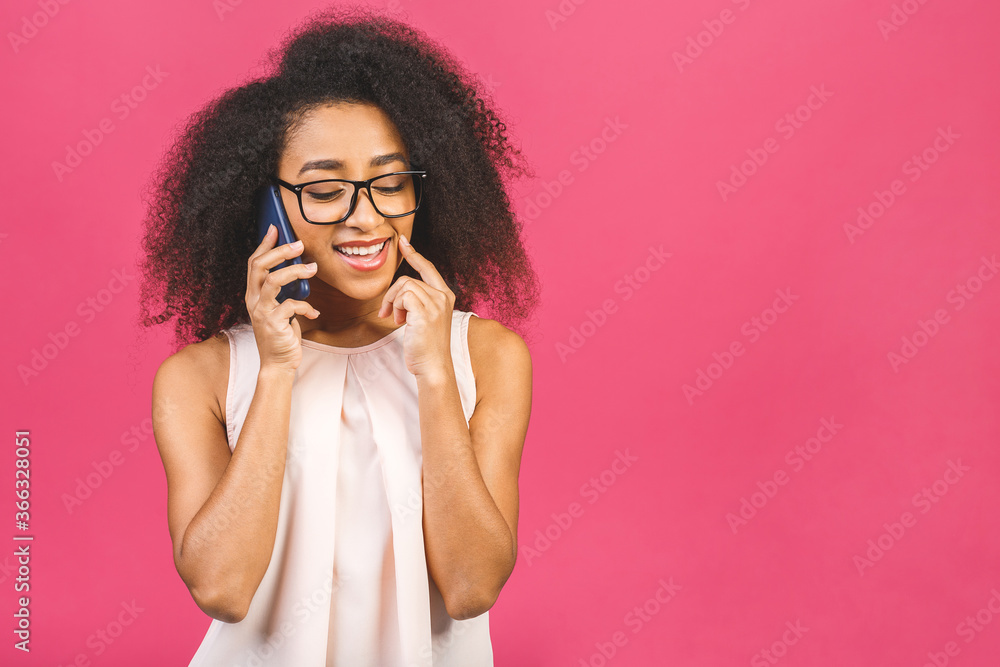 Portrait of a cute happy afro american black girl in casual talking on mobile phone and laughing isolated over pink background. Portrait of a cute happy afro american black girl in casual talking on mobile phone and laughing isolated over pink background.