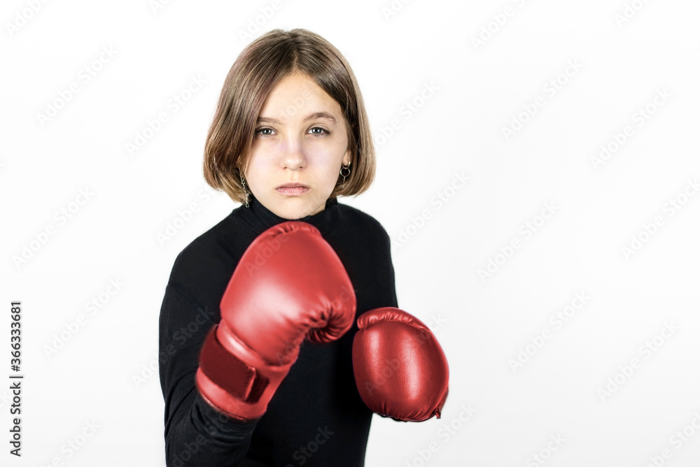 A young teenage girl loves sports and now she is learning new punches and improving her technique in boxing gloves. Girl in boxing gloves with a serious face A young teenage girl loves sports and now she is learning new punches and improving her technique in boxing gloves. Girl in boxing gloves with a serious face