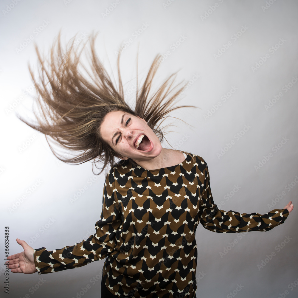 ragazza divertente con maglia fantasia balla e finge di suonare uno strumento musicale muovendo i capelli come una pazza, isolata su sfondo bianco ragazza divertente con maglia fantasia balla e finge di suonare uno strumento musicale muovendo i capelli come una pazza, isolata su sfondo bianco