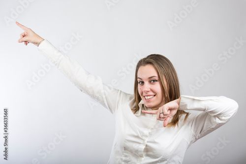 ragazza bionda con camicia bianca gioca divertita mentre gesticola , isolata su sfondo bianco