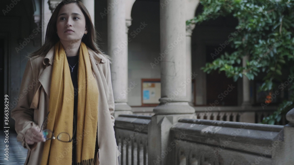 Naklejka premium Student walking in colonnade hallway.Businesswoman putting on eyeglasses outside