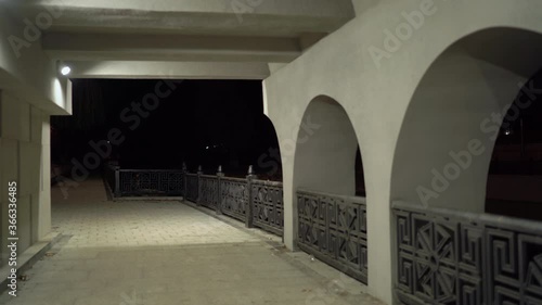 Pedestrian passage under the bridge on Salgir river embankment in Simferopol at night. Empty paved footpath lit by lanterns in autumn. photo