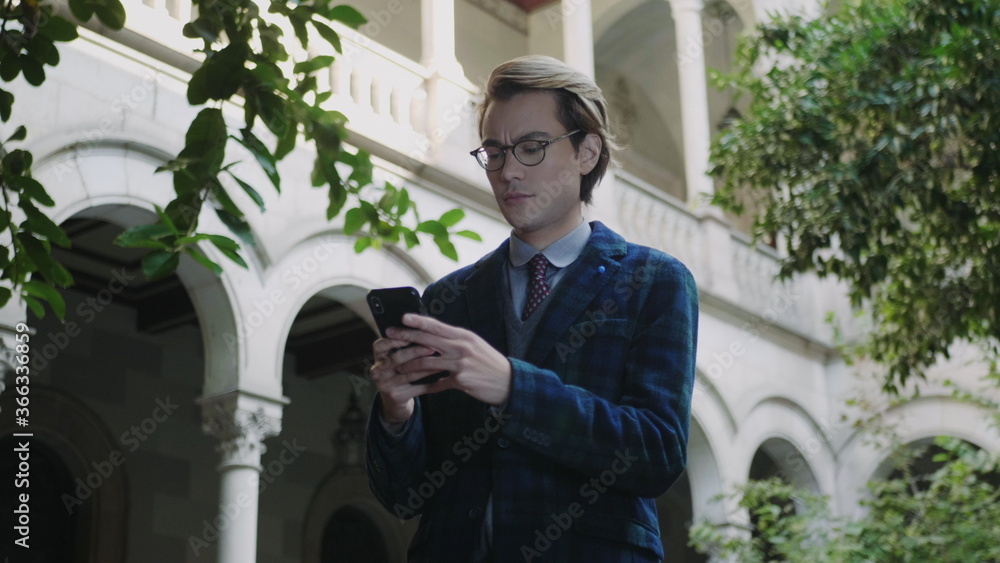 Student typing on smartphone. Businessman reading good news on phone outdoors Student typing on smartphone. Businessman reading good news on phone outdoors