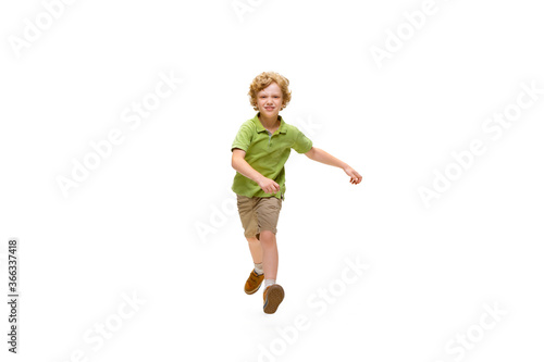 Happy child, little and emotional caucasian boy jumping and running isolated on white background. Looks happy, cheerful, sincere. Copyspace for ad. Childhood, education, happiness concept.