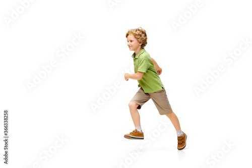 Happy child, little and emotional caucasian boy jumping and running isolated on white background. Looks happy, cheerful, sincere. Copyspace for ad. Childhood, education, happiness concept.