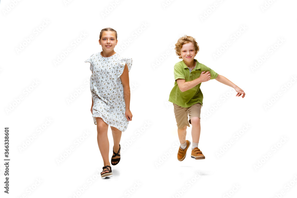 Happy children, little and emotional caucasian girl and boy jumping and running isolated on white background. Looks happy, cheerful, sincere. Copyspace for ad. Childhood, education, happiness concept. Happy children, little and emotional caucasian girl and boy jumping and running isolated on white background. Looks happy, cheerful, sincere. Copyspace for ad. Childhood, education, happiness concept.