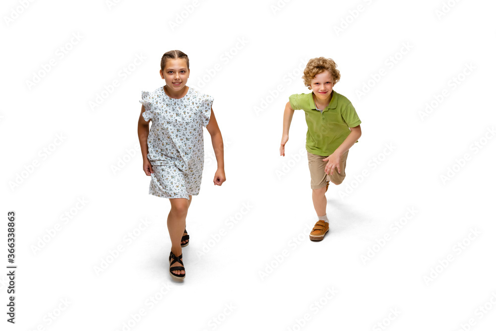 Happy children, little and emotional caucasian girl and boy jumping and running isolated on white background. Looks happy, cheerful, sincere. Copyspace for ad. Childhood, education, happiness concept. Happy children, little and emotional caucasian girl and boy jumping and running isolated on white background. Looks happy, cheerful, sincere. Copyspace for ad. Childhood, education, happiness concept.