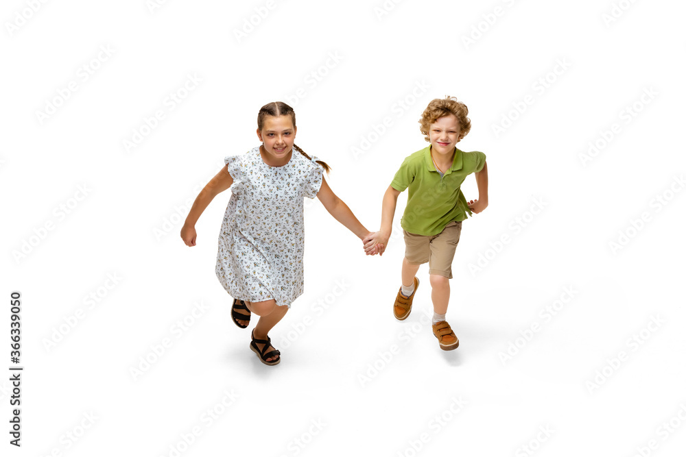Happy children, little and emotional caucasian girl and boy jumping and running isolated on white background. Looks happy, cheerful, sincere. Copyspace for ad. Childhood, education, happiness concept. Happy children, little and emotional caucasian girl and boy jumping and running isolated on white background. Looks happy, cheerful, sincere. Copyspace for ad. Childhood, education, happiness concept.