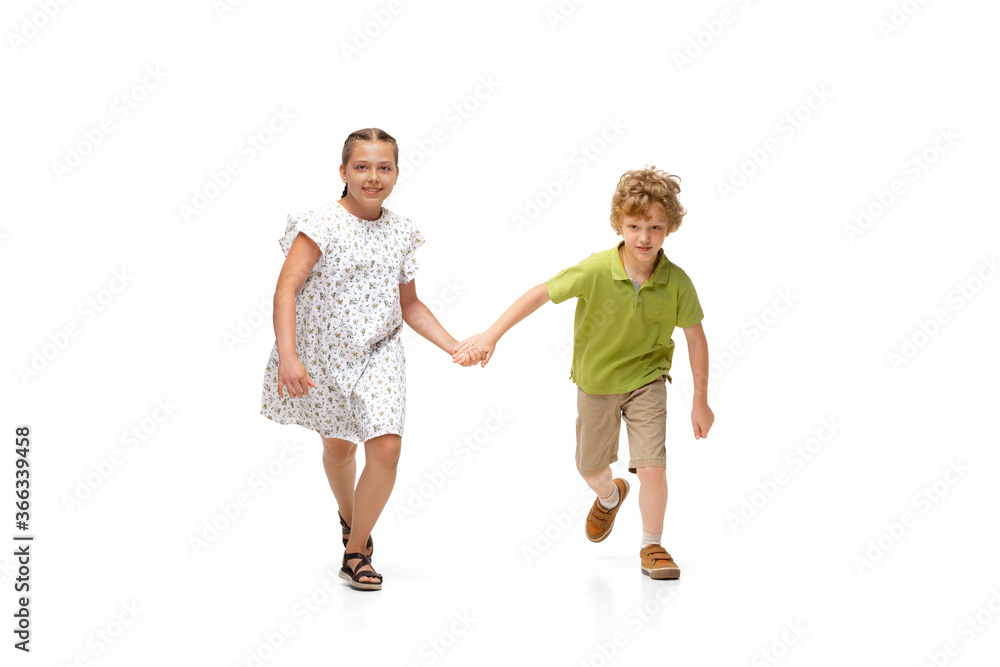 Happy children, little and emotional caucasian girl and boy jumping and running isolated on white background. Looks happy, cheerful, sincere. Copyspace for ad. Childhood, education, happiness concept. Happy children, little and emotional caucasian girl and boy jumping and running isolated on white background. Looks happy, cheerful, sincere. Copyspace for ad. Childhood, education, happiness concept.