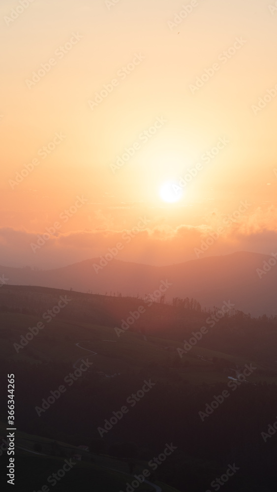 sunset between clouds and mountains in summer