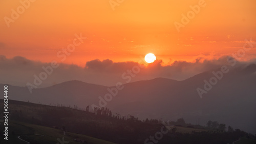 sunset between clouds and mountains in summer photo