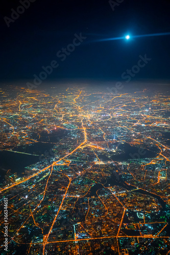 Aerial view to night city from the plane. Moon in the sky