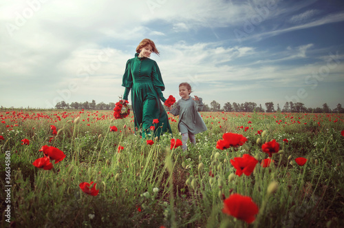 mom and daughter on a poppy field in the rays of the setting sun