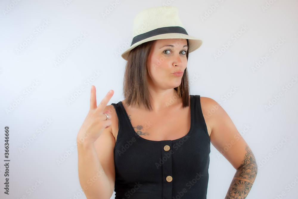 Beautiful young woman with hat making victory gesture Beautiful young woman with hat making victory gesture