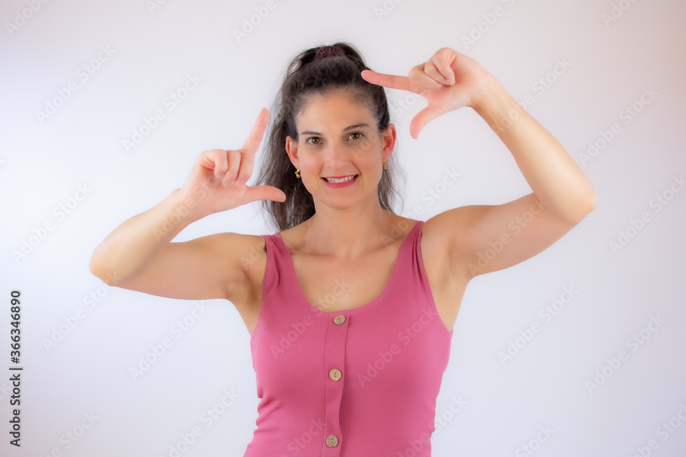 Beautiful young woman in pink shirt making portrait gesture Beautiful young woman in pink shirt making portrait gesture