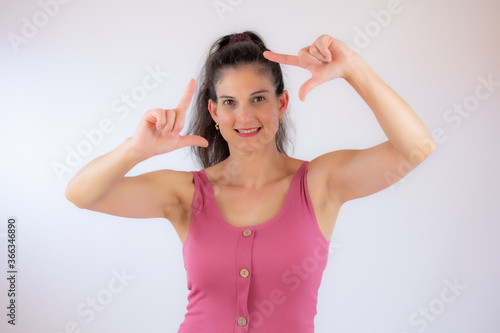 Beautiful young woman in pink shirt making portrait gesture © Danko