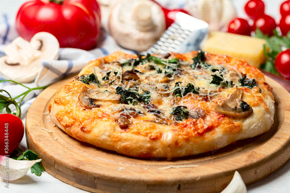 Pizza with tomatoes, mushrooms, cheese and green basil.