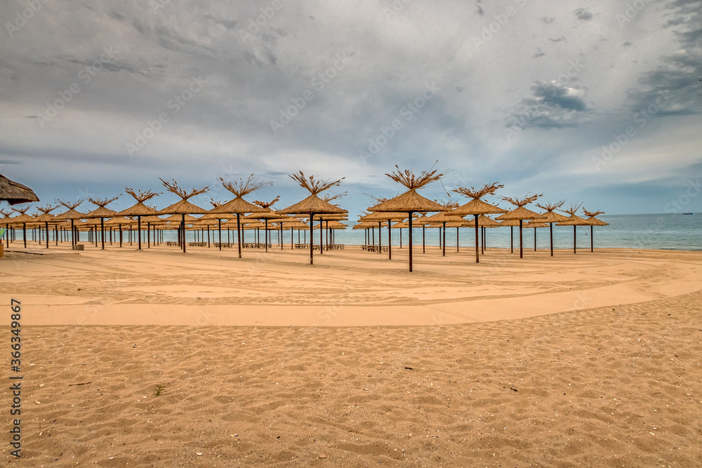 Beauty wooden umbrellas in a row of empty sandy beach