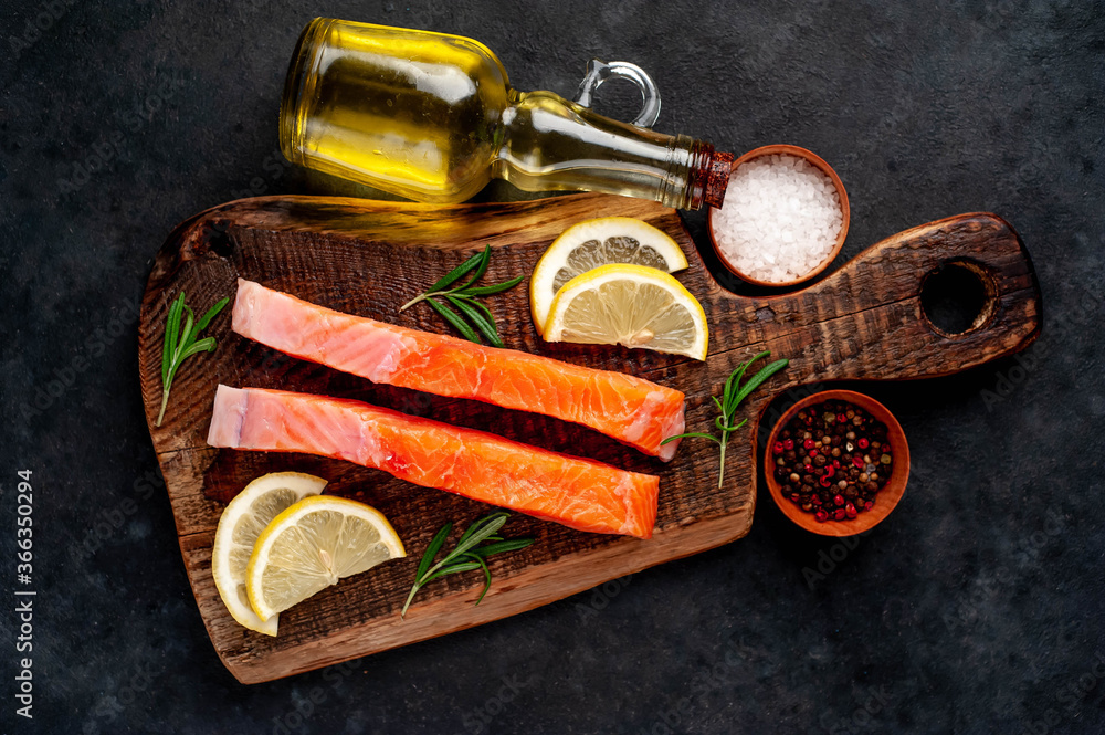 pieces of raw salmon with spices and lemon on a stone background pieces of raw salmon with spices and lemon on a stone background