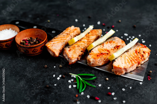 
grilled salmon slices over a meat knife on a stone background
