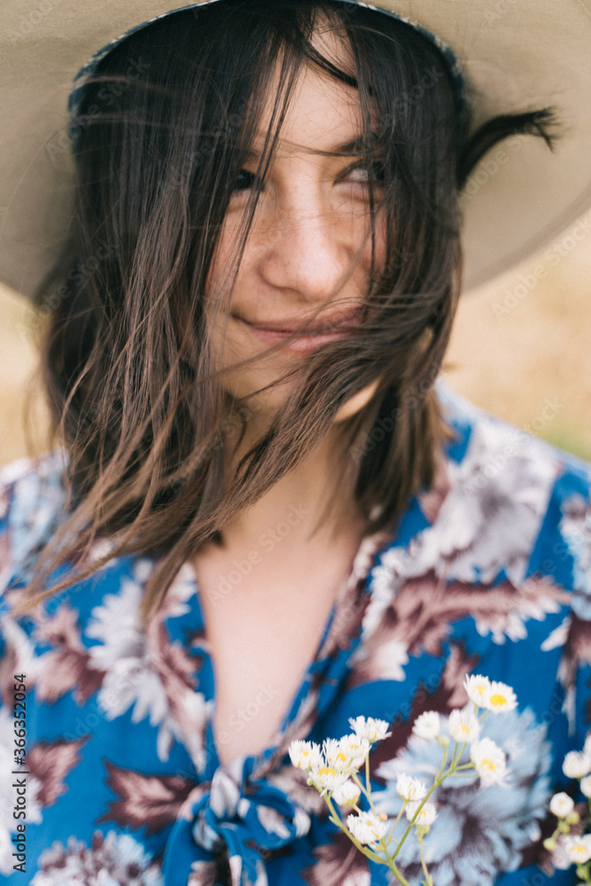 Sensual portrait of beautiful girl with windy hair. Calm young woman in blue vintage dress and hat relaxing in meadow. Tranquil summer in countryside Sensual portrait of beautiful girl with windy hair. Calm young woman in blue vintage dress and hat relaxing in meadow. Tranquil summer in countryside